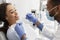 African woman attending dentist, doctor making check up