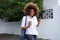 African woman with curly hair walking with mobile phone