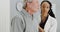 African woman doctor listening to elderly patient breathing