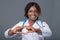 African woman doctor in a pink uniform, white coat and with a stethoscope holding a red heart. victory of the disease,