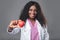 An African woman doctor in a white coat and with a stethoscope holds a red heart in her hands. cardiologist