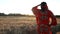 African woman farmer in traditional clothes standing in a field of crops at sunset or sunrise