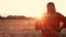 African woman farmer in traditional clothes standing in a field of crops, wheat or barley, in Africa at sunset or sunrise