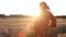 African woman farmer in traditional clothes standing in a field of crops, wheat or barley, in Africa at sunset or sunrise