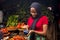 African woman selling food stuff in a local market smiling while using a mobile point of sale device