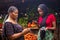 African woman shopping food stuff in a local market paying by doing mobile transfer via phone for a trader