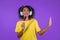 African woman singing and dancing with hair brush or comb instead microphone at purple studio background. Teenager in