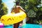 African woman standing by the pool with inflatable tube enjoying