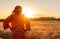 African woman in traditional clothes standing in a field of crops at sunset or sunrise