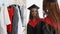 African woman trying on, fitting cap and gown and looking in mirror with happy smile Spbi. put on