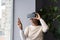 African woman wearing VR helmet touching air with finger, testing modern hi-tech future gadget