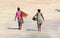 African women walking over the beach with laundry