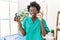 African young physiotherapist woman holding hand grip to train muscle doing ok sign with fingers, smiling friendly gesturing
