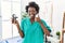 African young physiotherapist woman holding hand grip to train muscle smiling happy and positive, thumb up doing excellent and