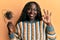 African young woman holding comb loosing hair doing ok sign with fingers, smiling friendly gesturing excellent symbol
