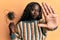 African young woman holding comb loosing hair with open hand doing stop sign with serious and confident expression, defense