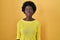 African young woman standing over yellow studio angry and mad screaming frustrated and furious, shouting with anger