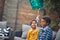 Afro-american brother and sister sitting together outdoor and play with balloon