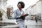 Afro american business lady writing on clipboard outdoors