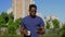 Afro-American businessman in wireless earphones uses smartphone drinking coffee