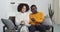 Afro american couple friends girl and guy sitting together in living room eating popcorn listening to music on radio