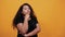 Afro-american curly woman keeping hand on chin, looking at camera, thinking