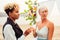 Afro american female in the role of the groom and short blonde haired bride in blue dress in ceremony under wedding arch