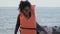 Afro-American girl in boat taking off life jacket, surviving after shipwreck