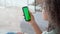 Afro American girl holding cell phone with green blank empty mockup screen.