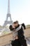 Afro american handsome man and caucasian girl hugging on stairs, Eiffel Tower in background, Paris.