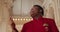 Afro american male gospel singer in 30s. Close up view of man wearing red suit singing spiritual music while standing in