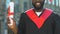 Afro-american male student in magister suit holding diploma, modern education