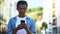 Afro-American male teenager chatting smartphone outdoors, online communication