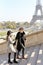 Afro american man and caucasian girl in hat walking on stairs, Eiffel Tower in background, Paris.