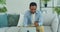 Afro american man holding plastic credit card in hand, entering payment data in computer application, sitting on sofa