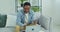 Afro american man holding plastic credit card in hand, entering payment data in computer application, sitting on sofa