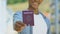 Afro-american man holding red passport, migration policy, simplified visa regime