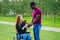 Afro american man marriage proposal giving a ring to his redhaired ginger girlfriend.she sitting on wheel chair and