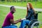 Afro american man marriage proposal giving a ring to his redhaired ginger girlfriend.she sitting on wheel chair and