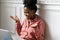 Afro-American millennial biracial woman working on laptop, gesturing with hands, looking at camera webcam and chatting and talking