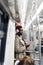 Afro-American passenger man in red hat, trench coat stand in subway train, using mobile smart phone, listens to music with