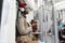 Afro-American passenger man in red hat, trench coat stand in subway train, using mobile smart phone, listens to music with