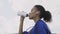 Afro-american runner woman Drinking Water or isotonic After Running. Portrait Fitness Woman Drinking Water From Bottle.