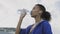 Afro-american runner woman drinking water after running. Portrait fitness woman drinking water from bottle.