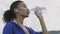 Afro-american runner woman Drinking Water After Running. Portrait Fitness Woman Drinking Water From Bottle.