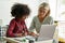 Afro American schoolgirl learning with female tutor teacher using laptop.