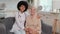 Afro american woman doctor and patient senior woman sitting on sofa and smiling