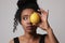 Afro American woman with lemon on white wall for skin and body care. Isolated.