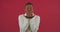 Afro american woman mixed race girl stands posing on red background in studio wears white sweater sends air kiss makes