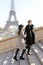 Afro american young man and caucasian girl walking on stairs, Eiffel Tower in background, Paris.